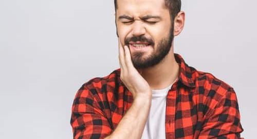 frowning man holding jaw with tooth pain