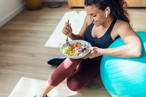 shot,of,sporty,young,woman,eating,healthy,while,listening,to