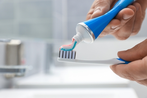 man,applying,toothpaste,on,brush,in,bathroom,,closeup.,space,for