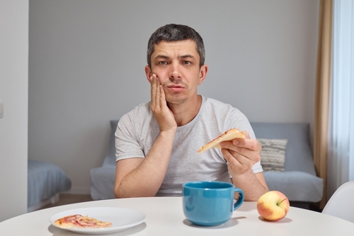 disappointed,upset,young,man,holding,piece,of,pizza,feeling,teeth